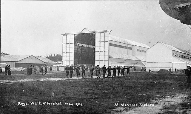 Farnborough - A line of mainly sailors (with a few soldiers) holding on to a rope attached to an airship, the corner of which is just visible in the photograph. The airship shed is visible in the background.