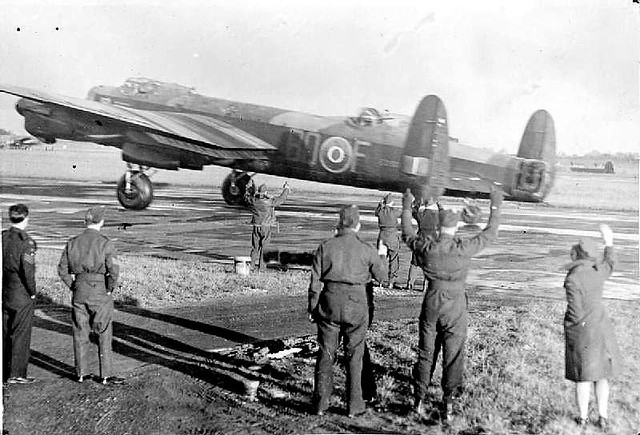 RAF and WAAF personnel wave off Flight Lieutenant D A Shaw and crew of No. 550 Squadron RAF as they take off for a bombing raid on Bochum, Germany, from North Killinghome, Lincolnshire, in Avro Lancaster B Mark III, ED905 'BQ-F' 