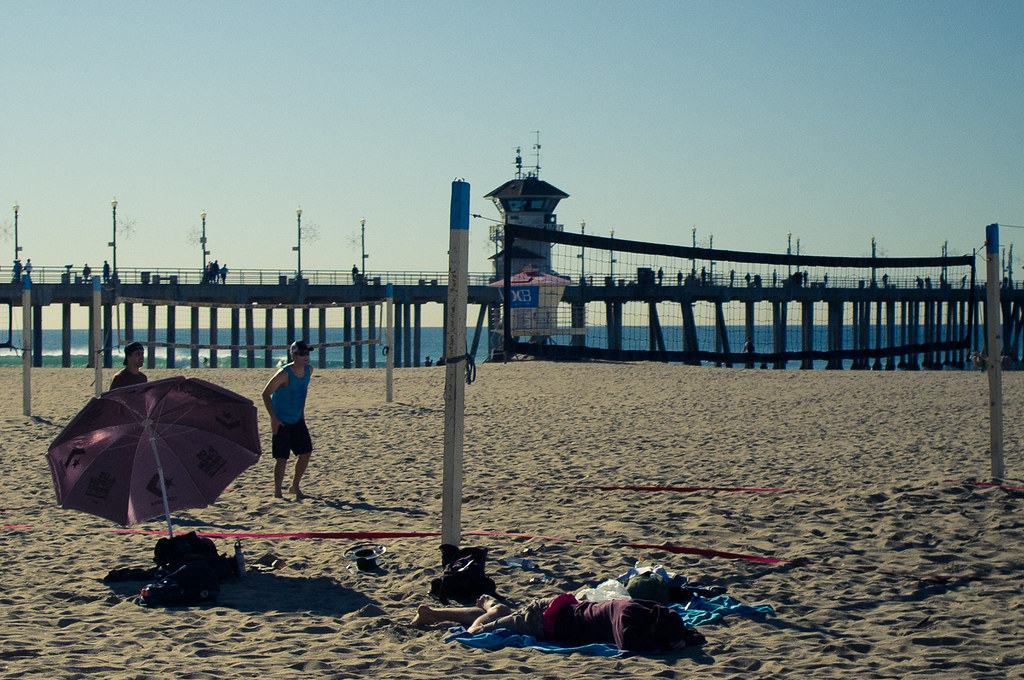 Sunny California beach volleyball court looking toward the Huntington Beach Pier and lifeguard tower.