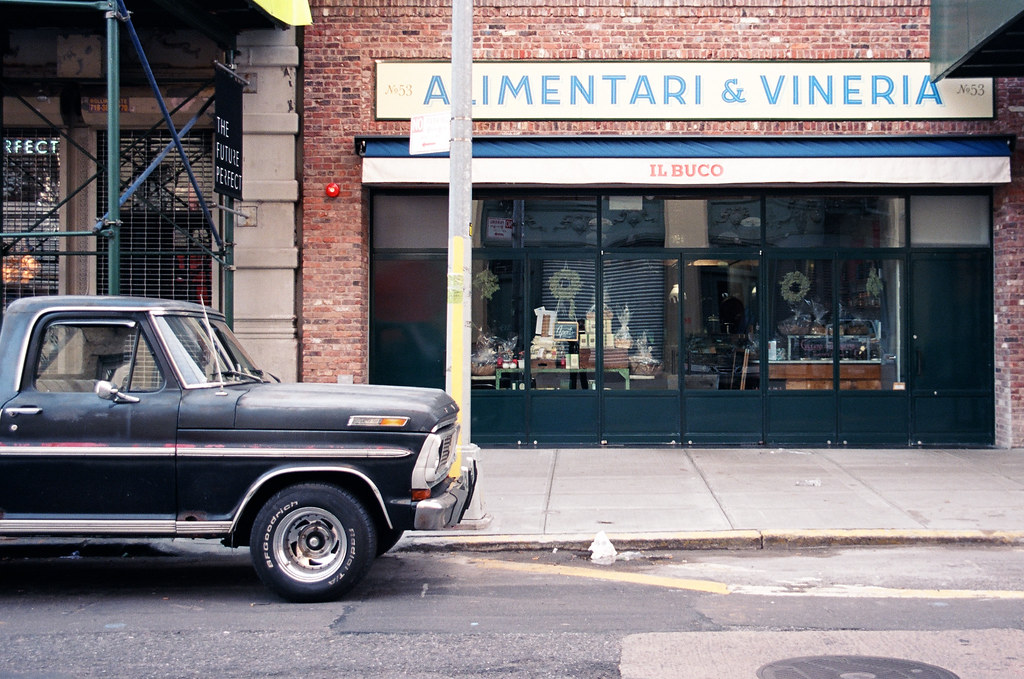 Dark Ford pickup truck parked curbside outside the brick storefront of Il Buco Alimentari in Manhattan.