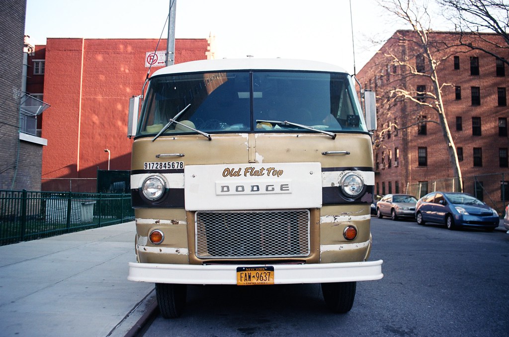 Front view of a vintage gold and white Dodge camper van nicknamed 'Old Flat Top' parked along a Brooklyn street.
