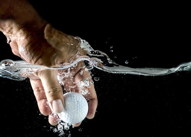 hand take up Golf ball  splashing in water.