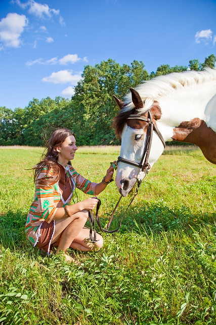 A young girl dressed as an Indian walking with a paint horse
