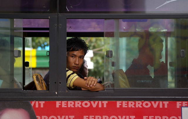 A passenger looks out from the window of a bus, Yangon (Rangoon), Myanmar (Burma)