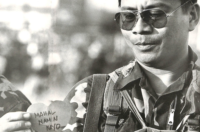 A marine officer accepts a cut-out heart, as the people continue to cajole the Marcos troops to join them in the popular uprising