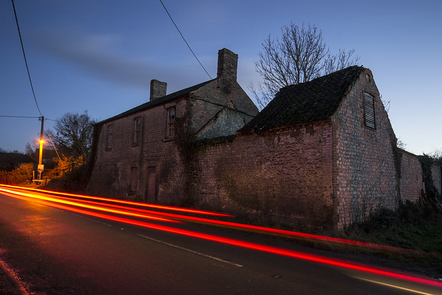 Light trails in front of derelict house