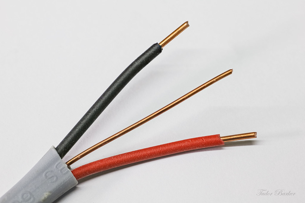 Electrical cable opened with a red, black, and copper wire