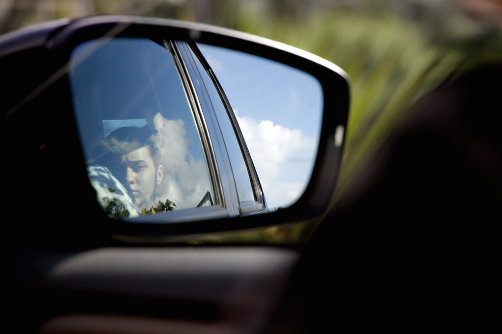 شاب ذو تعبير جاد ينظر من خلال نافذة السيارة.