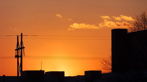 Day’s End by DewCon, Buildings, trees and power lines silhouetted against the light of a setting sun in La Crosse, Wiscon