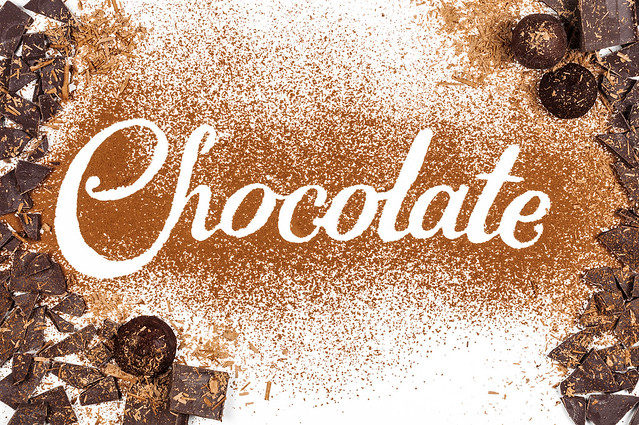 The word Chocolate written by cocoa powder with dark chocolate and candies