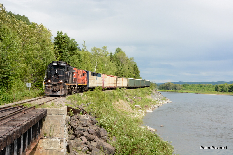 Societe Du Chemin De Fer De La Gaspésie Train 595 is running off the last few miles of the Casapedia Sub. on its way to Matapedia, Quebec.  Here the train is running alongside the Chaleur Bay with RS-18 # 1865 and 1819 and 15 loads of lumber and chips.  Listuguj, Quebec June 23, 2016.  The power is still painted for former owners ( Ottawa Central and CP ), but with a name like that we will have to shorten it up to fit on the units if paint is ever in the future ?   
