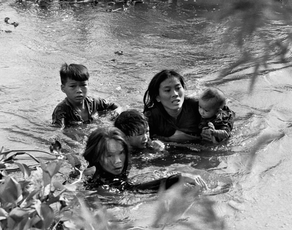 Vietnamese civilians cross a river to escape attack on village