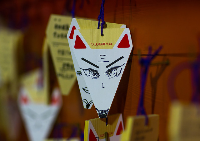 Folded paper fortunes with fox head tied to wires on a board at fushimi inari taisha shrine, Kansai region, Kyoto, Japan