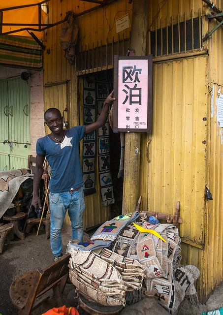 Ethiopian man in front of a billboard in chinese language to sell opales, Addis abeba region, Addis ababa, Ethiopia