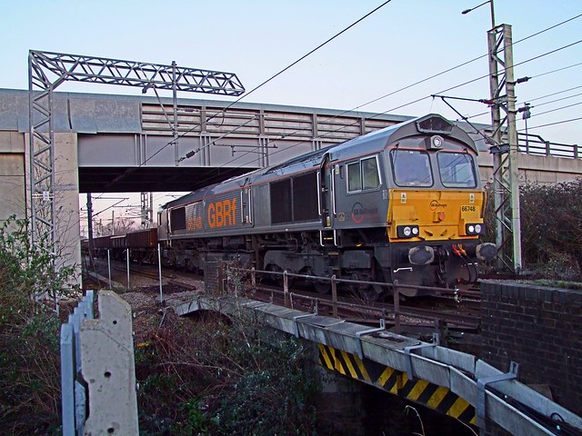 Ex Dutch Class 66 66748 sits at Rye House, Hoddesdon, under Essex Road Bridge, with a train of half filled spoil wagons. 18 01 2015