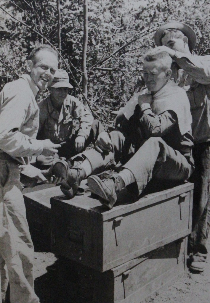 Photo of maneuvers. Lieutenant Zurcher getting hair cut. Parker shining shoes. DB Howard, barber.