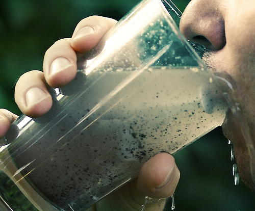 Close-up of a person taking a sip of dirty water.