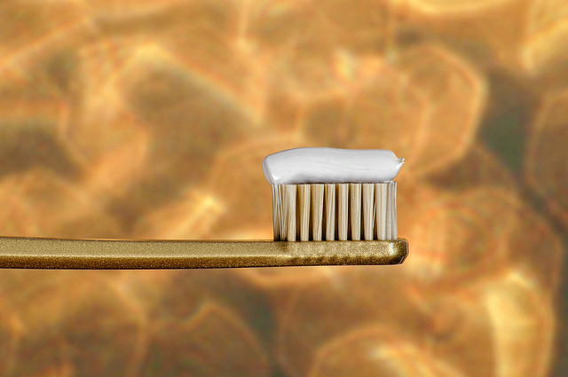 Tooth brush with tooth paste on golden bokeh background