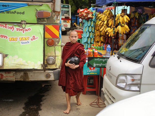 Bare feet little monk out on alms at Yangon bus station