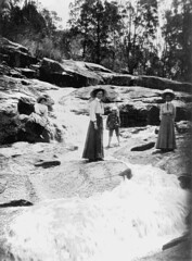 Elegantly dressed ladies and small child watching Winstead Falls flowing through granite rocks north of Stanthorpe, 1909