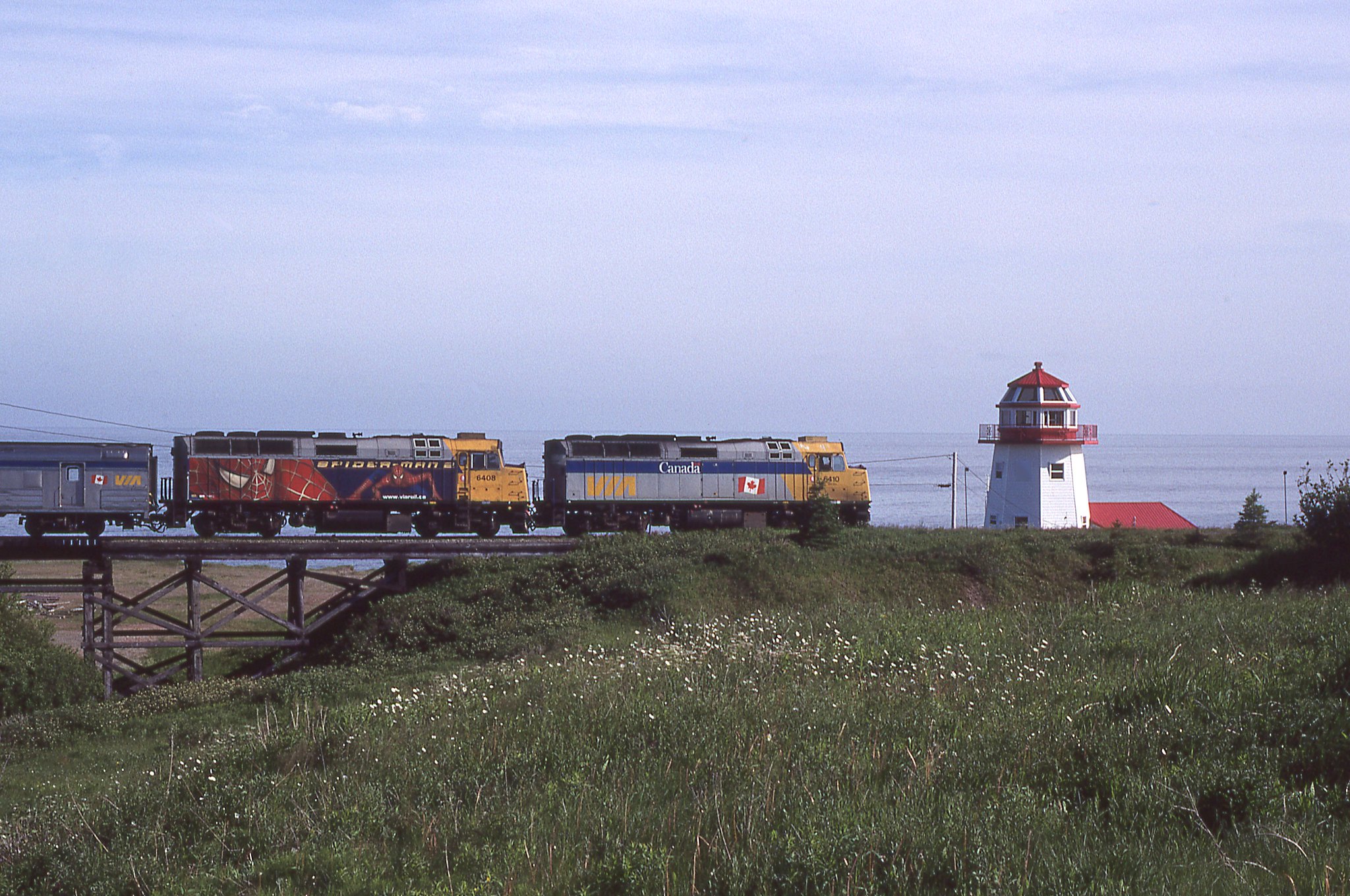 What looks like a regular lighthouse is really some ones creative home along the coast .VIA Westbound Chaleur with # 6410 leading passes by. Ste-Therese-de-Gaspe, Quebec June 28, 2008