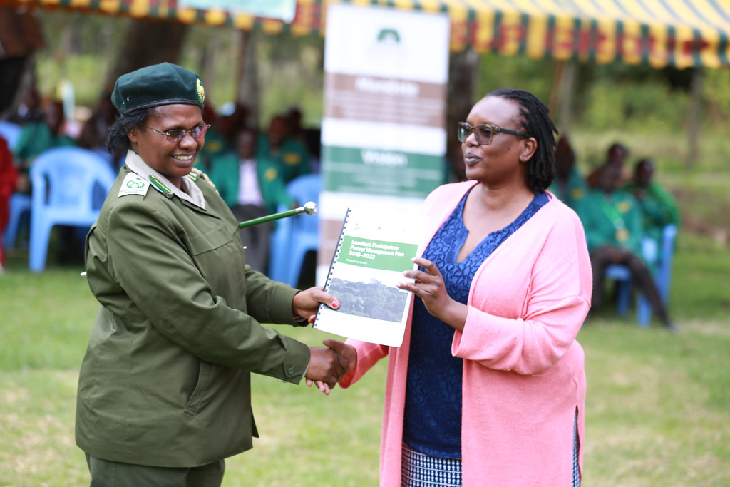Head of Management Plan Kenya Forest Service (KFS) Elizabeth Wambugu receiving the Participatory Forest Management Plan (PFMP).