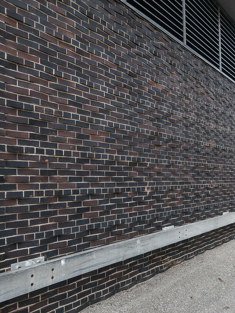 Absurdly subtle late-1950s brick pattern of angled-out protrusions of dark blue-black and purple-brown bricks.