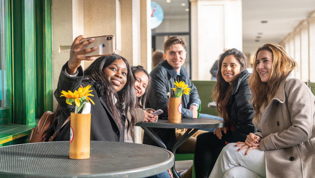A group of students taking a selfie at an outdoor table in the city