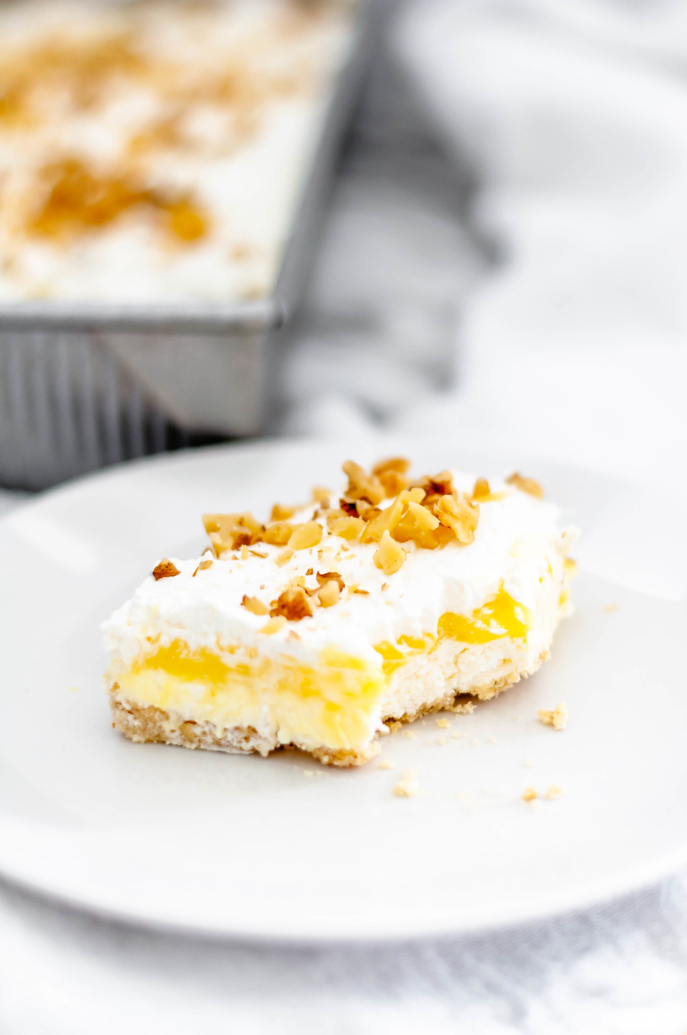 Lemon Hush is a delicious layered dessert of shortbread crust, cream cheese filling, lemon pudding, cool whip and chopped nuts. A family favorite.