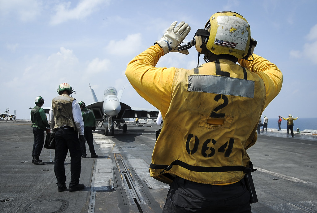 Aviation Boatswain's Mate (Handling) 1st Class Joshue Chinbritton directs a Boeing FA-18F Super Hornet onto a catapult on the flight deck of the USS Theodore Roosevelt.