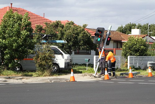 VicRoads contractors use a jack to try and bend the traffic signal post back into place