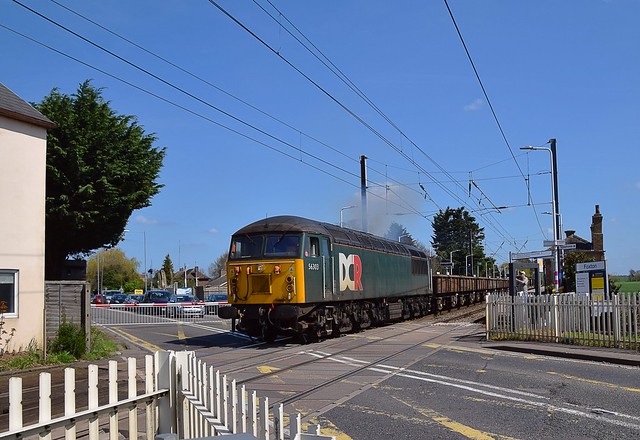 Loco 56303 powers away from Foxton, on the Great Northern Cambridge Branch, with the 11.23 Barrington to Willesden spoil empties. The road here is the busy A10. 18 04 2018