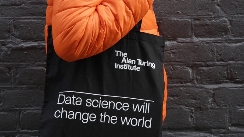 A person wearing an orange coat carrying a tote bag that reads 'Data science will change the world'