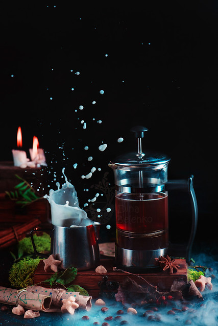French press with coffee and a milk jug on a dark background with a milk splash. Action food photography. Alternative coffee brewing concept.