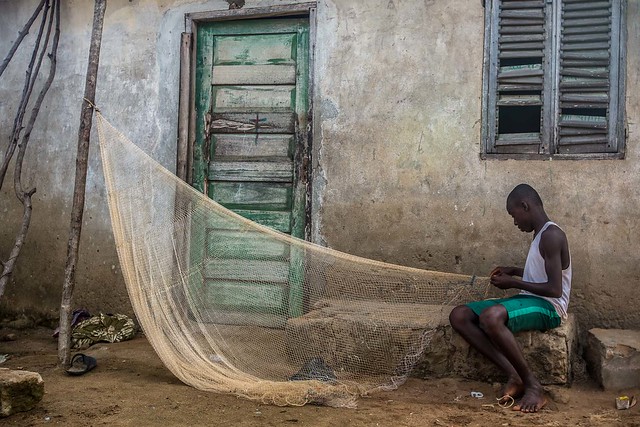 young fisherman adjusts his fishing net, a village on the coast of Ghana