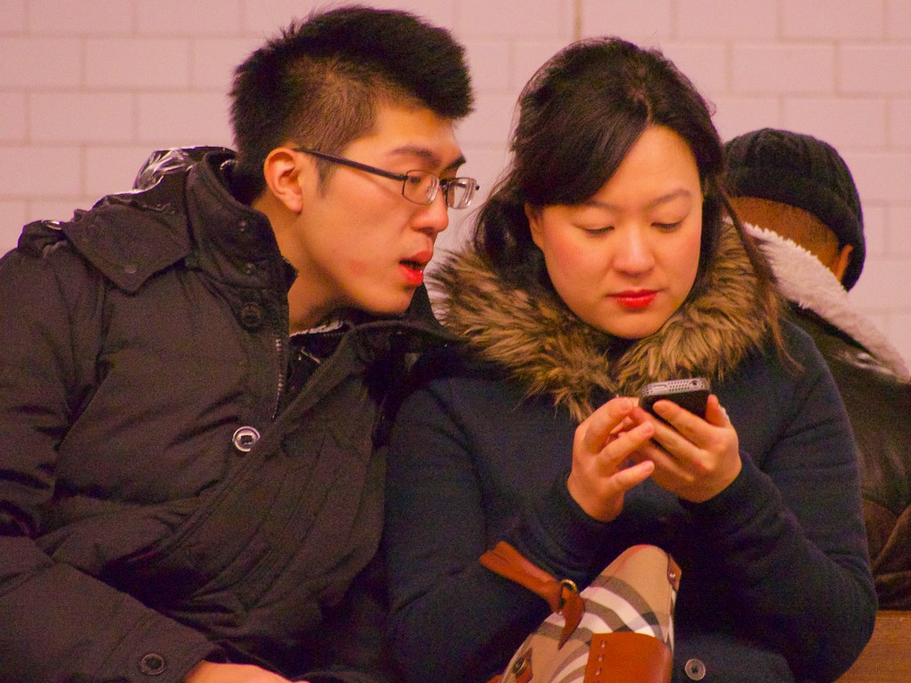 A man and a woman looking at a mobile device