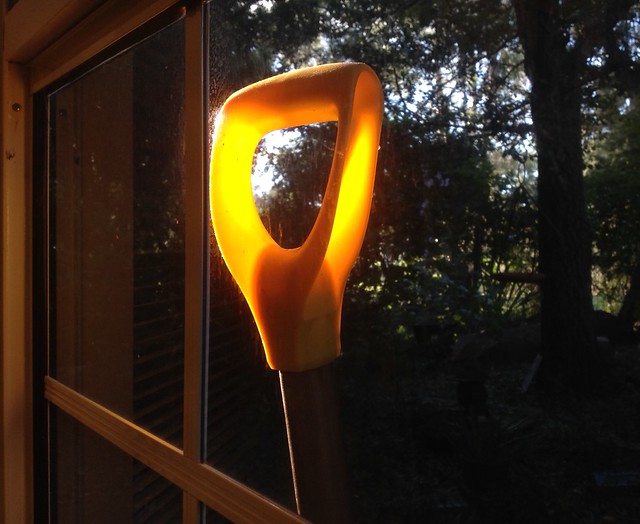 The afternoon sun backlights the plastic handle on the garden spade as it leans against the lounge window!