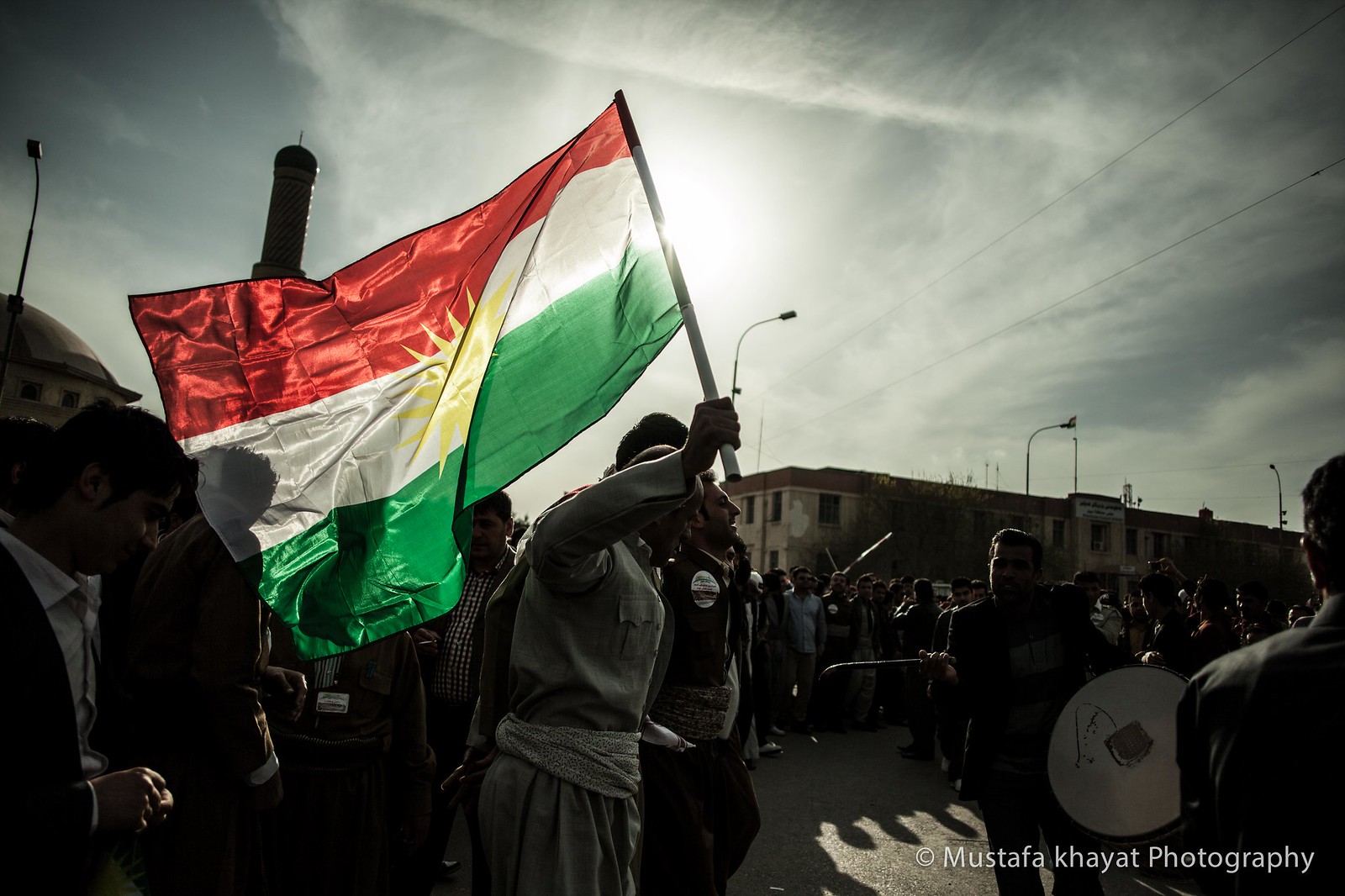 Ciudadano kurdo bailando mientras agita la bandera nacional de Kurdistán en Erbil