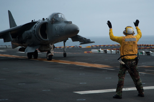 A Sailor directs an AV-8B aboard USS Boxer.