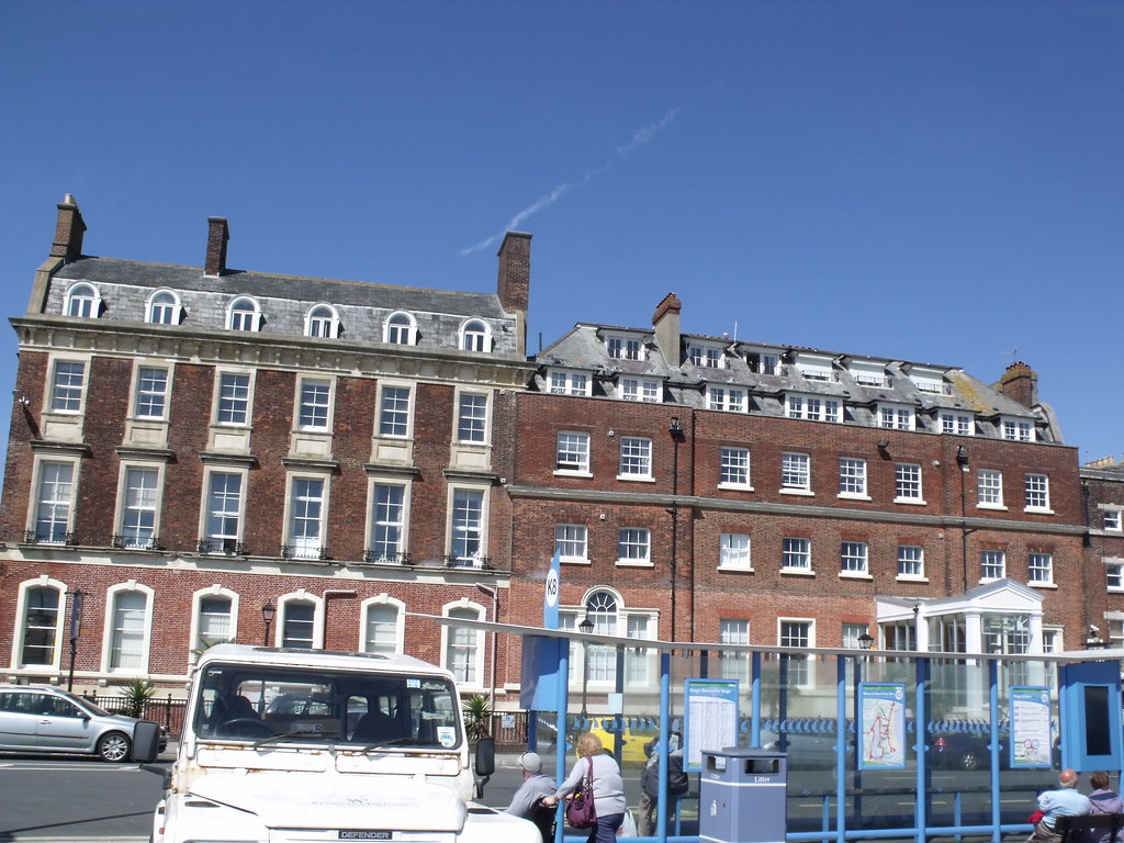 Photo of the Esplanade, in Weymouth England, which is a four-floored etate with big white windows. 