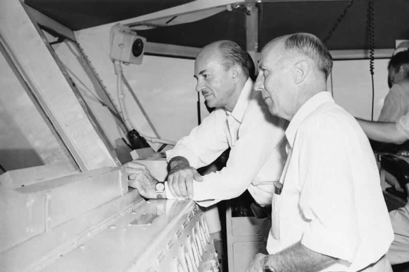 Governor Richard Lowe, 1956 – 1959, aboard the USS Yorktown at left with an unidentified man. An official photograph of the US Navy, courtesy of the Micronesian Area Research Center (MARC).