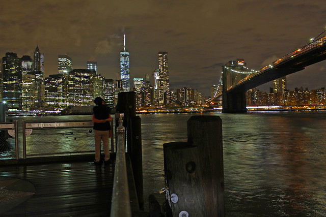 A Couple Beside the Brooklyn Bridge Leading into Lower Manhattan at Night