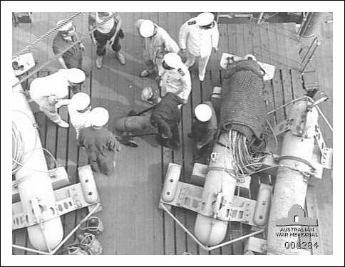 A group of officers and ratings of the crew of the Armed Merchant Cruiser HMAS Westralia inspecting a 250 lb bomb intended for use by the Supermarine Walrus amphibian aircraft carried on the ship.