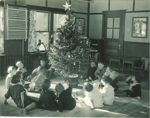 Children sitting around a Christmas tree in a classroom, The University of Iowa, 1920s