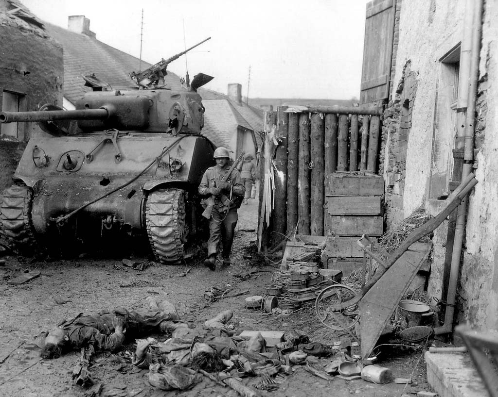 Knocked out M4 Sherman and in the foregrount dead german soldiers.