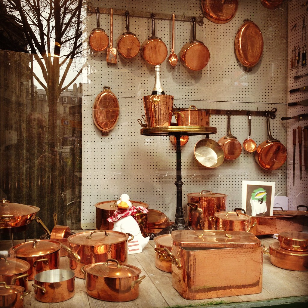 Shop window with wide variety of polished copper pots and pans