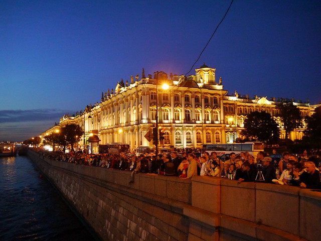 Crowd along the Neva River waiting for the Palace Bridge to be drawn. State Hermitage Museum in the background