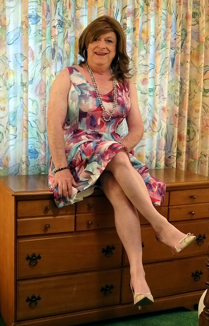 Redhead in floral satin dress seated on dresser