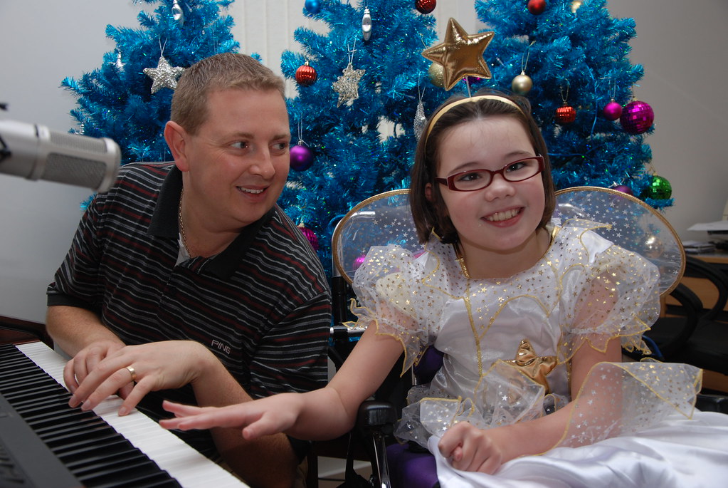 A man and young girl plays the piano. Both are smiling