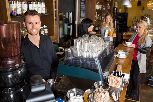 Male Bartender With Colleague Working In Background